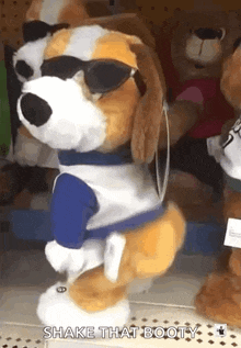 a stuffed dog wearing sunglasses and a blue shirt is dancing and says shake that booty .