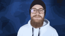 a man with a beard wearing glasses and a beanie with a world map in the background