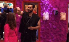 a man and a woman are standing next to each other in front of a purple wall .
