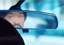 a man with a mustache is looking at himself in the rear view mirror of a car