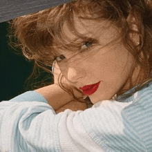 a close up of a woman 's face with red lips and a hat on .