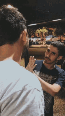 a man wearing a t-shirt that says ' abercrombie & fitch ' on it talks to another man