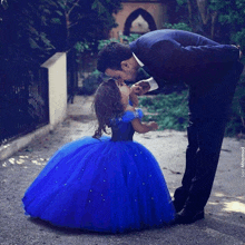 a man kisses a little girl on the cheek in a blue dress