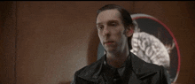 a man in a leather jacket is talking to a robot voice and asking him to get on top of him .