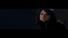 a woman in a black turtleneck is smiling in a dark room