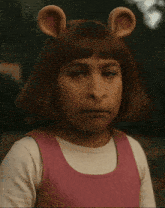 a little girl wearing a pink dress and ears is making a face
