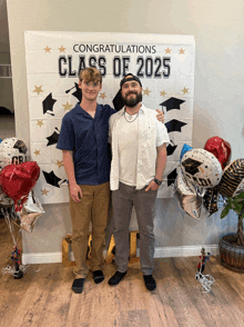 two men are standing in front of a banner that says congratulations class of 2025