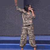 a woman in a plaid suit is singing into a microphone on a stage