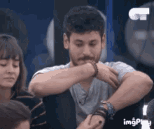 a man with a beard is sitting in a chair with his hands on his face .
