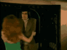 a woman in a green dress is dancing with her arms in the air