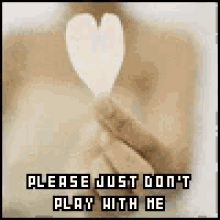 a person is holding a heart in their hand with the words `` please just don 't play with me '' written on it .