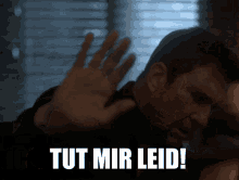 a man is making a stop gesture with the words tut mir leid below him