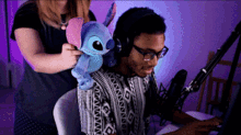 a woman holding a stuffed stitch behind a man 's back