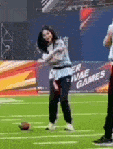 a woman is standing on a football field holding a ball .
