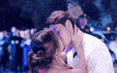 a man and woman kissing in front of a crowd of people