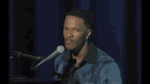 a man singing into a microphone while sitting at a piano