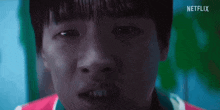 a close up of a young boy 's face with a netflix logo behind him .