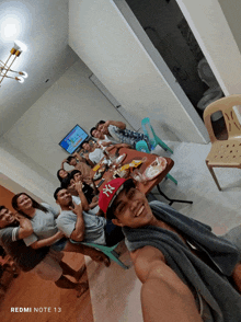 a group of people gathered around a table with a redmi note 13 on the bottom right