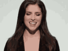 a woman with long brown hair is smiling and making a funny face .