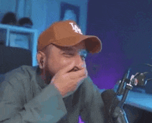 a man with a beard is sitting in front of a microphone and covering his nose .