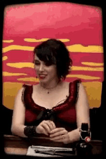 a woman in a red dress sits at a table