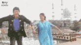 a man and a woman are dancing in front of a mosque while holding hands .