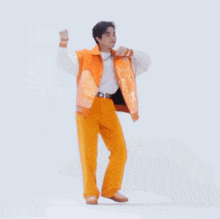 a man in an orange jacket and yellow pants is dancing .