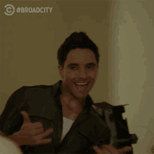 a man is smiling in front of a sign that says broad city