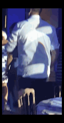 a man in a white shirt is standing in front of a table