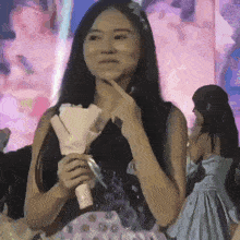 a woman in a black dress is holding a bouquet of roses