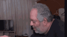 a man with a beard is sitting in front of a television .