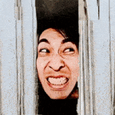 a man is making a funny face while looking through a hole in a wall .