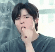 a young man is covering his mouth with his hand while making a funny face .