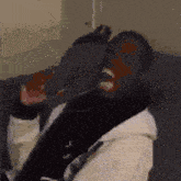 a man is sitting on a couch with his mouth open and a bird on his head .