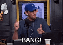 a man wearing a blue hat and ear buds is saying bang