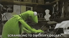 kermit the frog is standing in front of a typewriter in a room with a statue in the background .