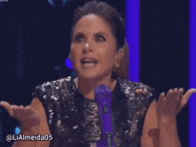 a woman speaking into a purple microphone with the username lialmeida05 on the bottom