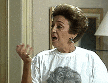 an elderly woman wearing a white t-shirt with a picture of a woman on it
