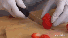 a person wearing white gloves is cutting strawberries on a cutting board made in animatica