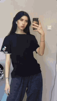 a girl is taking a selfie in front of a mirror .