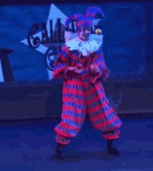 a man in a clown costume is standing on a stage in front of a sign that says alloway circus