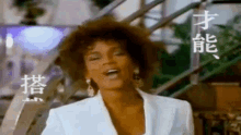 a woman in a white jacket and earrings is standing in front of stairs .