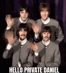 the beatles are waving their hands in the air while standing next to each other .