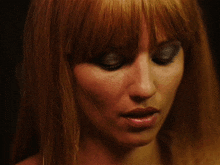 a close up of a woman 's face with red hair and blue eyeshadow