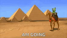 a gummy bear is riding a camel in front of pyramids in the desert .