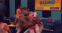 a man is carrying a woman in front of a sign that says gizmo show