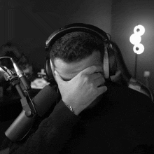 a man wearing headphones is covering his face with his hand