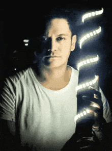 a man in a white t-shirt is holding a light in his hand