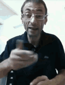 a man wearing glasses and a black shirt with the word lacoste on the front