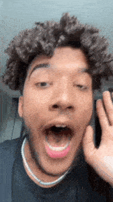 a young man with curly hair is making a funny face with his mouth open .
